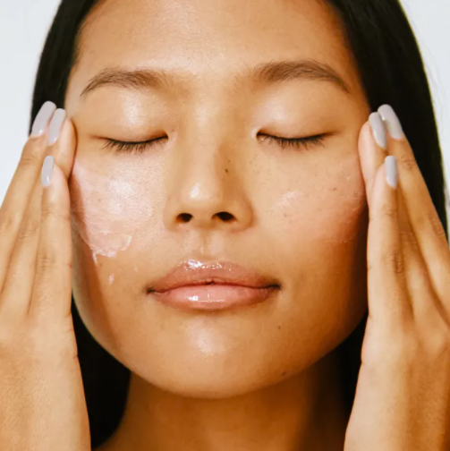 Woman happily applying her dry skin face moisturizer